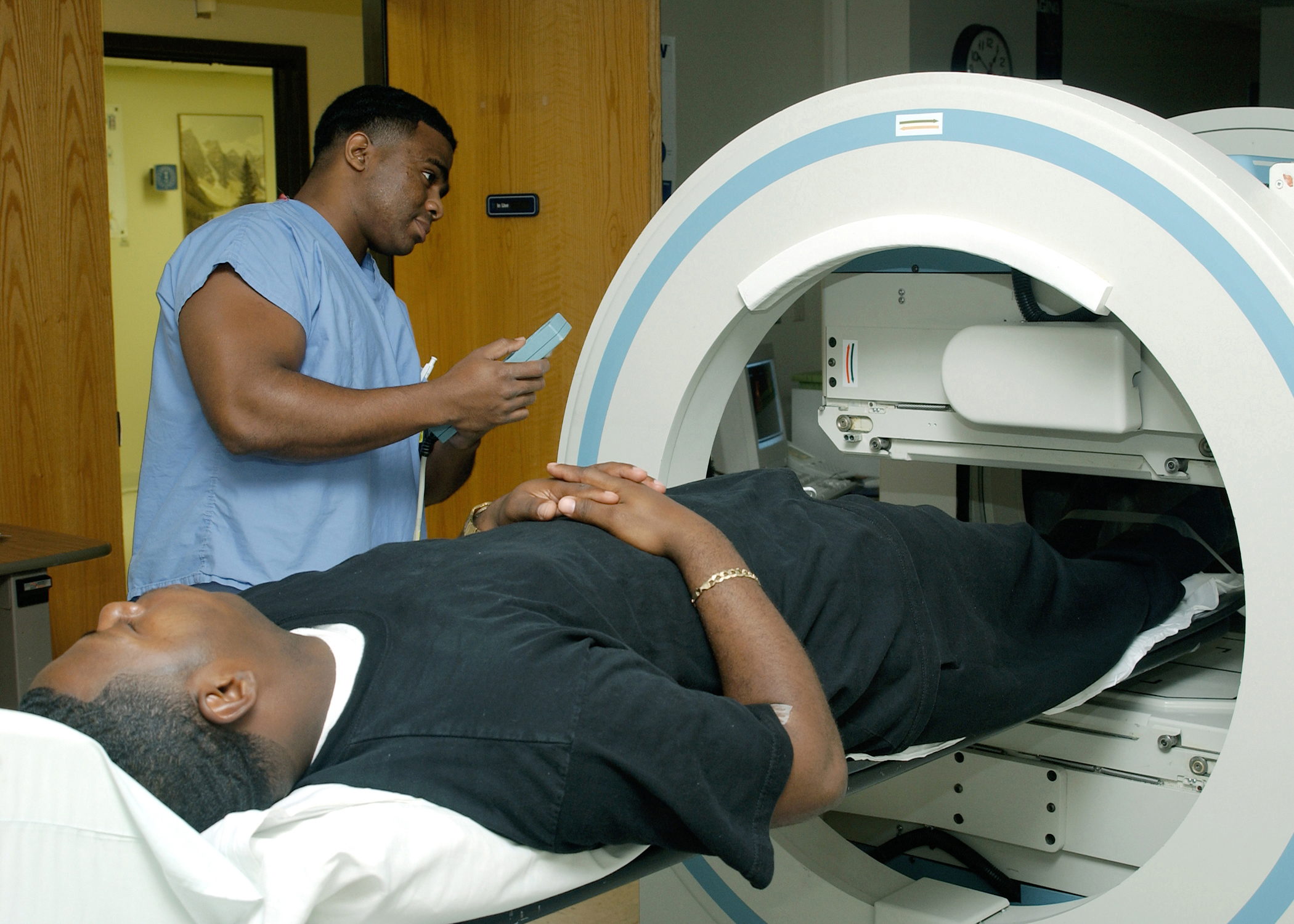 Man laying on table with feet in medical camera chamber with a physician looking on